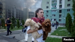 Жена со своите кучиња го напушта местото на рускиот воздушен напад, за време на рускиот напад врз Украина, во Харков, Украина, на 24 јули 2025 година.