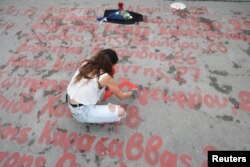 O femeie scrie numele victimelor accidentului feroviar, în fața parlamentului, 28 februarie.