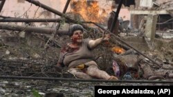 Ranjena Gruzijka leži sa drugim ljudima ispred stambene zgrade, oštećene u ruskom vazdušnom napadu, u gradu Gori na sjeveru Gruzije, 9. avgusta 2008.