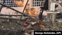 Грузија- Ранета Грузијка лежи со други луѓе пред станбена зграда, оштетена од руски воздушен напад, во северниот грузиски град Гори, 9 август 2008 година