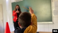 Ученик и наставничка со заштитни маски на час во време на пандемија