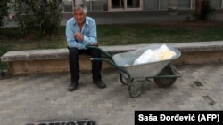 Egy albán nemzetiségű férfi pihen a „Bojkottáld a népszámlálást” földre festett felirat előtt, a dél-szerbiai Bujanovac városban, 2011. október 1-én