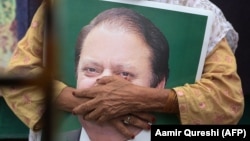 FILE: A supporter of former Pakistani Prime Minister Nawaz Sharif holds his picture at Lahore airport ahead of his arrival in July 2018.