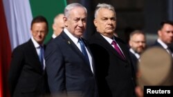 Prim-ministrul israelian Beniamin Netanyahu și premierul ungar Viktor Orbán privesc garda de onoare în timpul unei ceremonii de bun venit la Curtea Leului din Budapesta pe 3 aprilie.