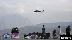 Военен хеликоптер прелита над продавачи на хвърчила в Кабул, Афганистан