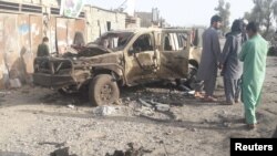 Residents look at an Army vehicle destroyed in fighting between Afghan security forces and Taliban in Farah city on May 16.