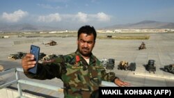 Un soldat afgan se fotografiază în Baza aeriană Bagram pe care forțele afgane au găsit-o părăsită peste noapte.