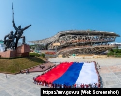 Развертывание флага России на фоне строящегося театра оперы и балета в Севастополе, 12 июня 2025 года