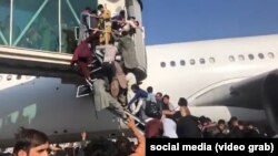 Desperate Afghans attempt to board a plane at Hamid Karzai airport in Kabul on August 16 after the Taliban had seized the city. 