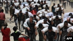 Palestinieni cărând saci cu făină în apropiere de Jabalia, în nordul Fâșiei Gaza, pe 27 iulie 2025, după ce camioane cu ajutoare umanitare au intrat în nordul Fâșiei Gaza venind de la punctul de trecere a frontierei Zikim.