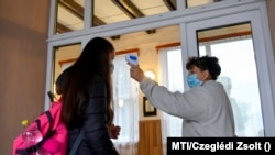Egy diák testhőmérsékletét mérik érkezéskor a Bagaméri Általános Iskola és Alapfokú Művészeti Iskola bejáratában, 2020. szeptember 29-én