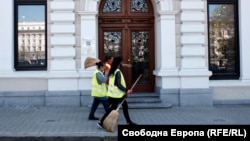 10 април 2020 г. Работници по поддържане на чистотата преминават покрай централата на Българската банка за развитие в София.