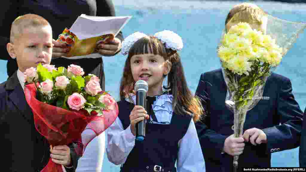 Після виконання державного Гімну України першокласники читають святкові вірші. Читає і Даша Водінова. Вірші та навчання українською мовою не є проблемою для дитини, хоча і переїхали вони зі, здебільшого, російськомовного міста Антрацит на Луганщині. Для батьків спілкування українською теж не становить проблем, хоча між собою вони говорять російською