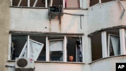 Un bărbat privește pe fereastra unui apartament avariat de o lovitură rusească cu dronă la Kiev, pe 6 iunie, în zori.