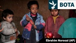 Tre fëmijë afganë të zhvendosur brenda vendit shohin me habi një mollë që nëna e tyre e solli në shtëpi pasi kishte kërkuar lëmoshë.