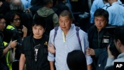 Magnatul media din Hong Kong Jimmy Lai, centru, este luat de ofițeri de poliție în zona ocupată din afara sediului guvernului din Hong Kong.