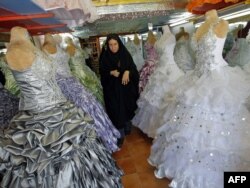 Иранка проходит среди висящих в магазине свадебных платьев.