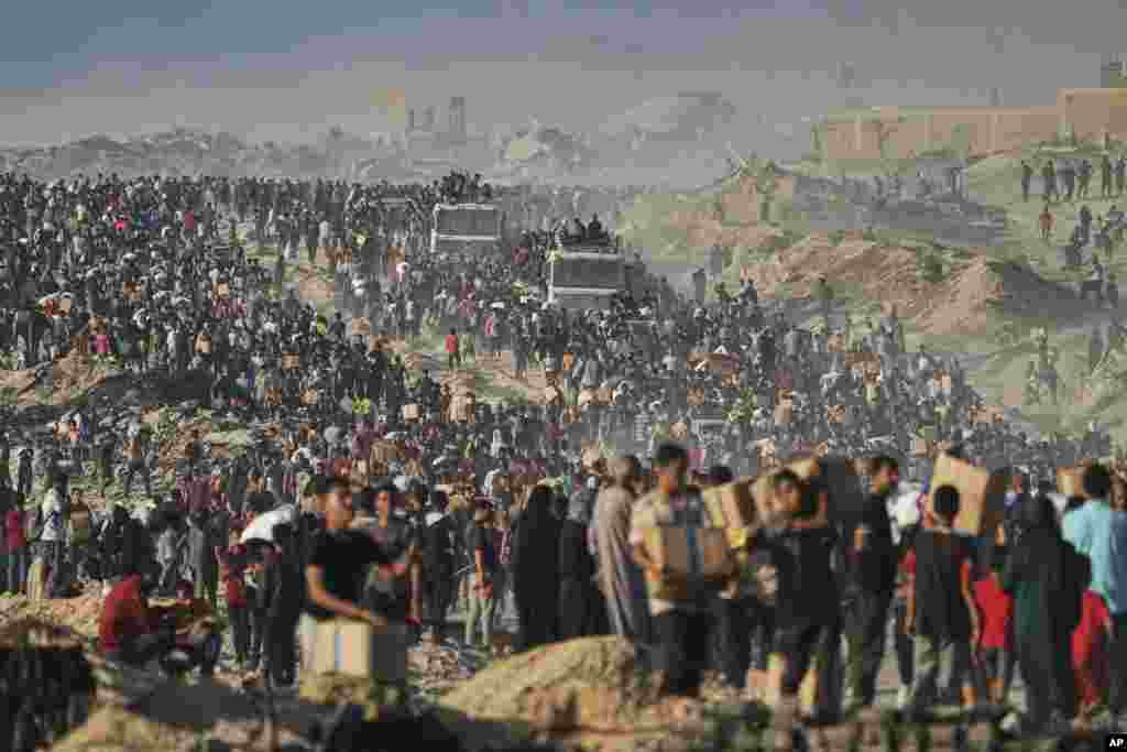 Palestinezë duke bartur thasë dhe pako me ushqime dhe ndihma tjera humanitare, që u shkarkuan nga një karvan kamionësh të Programit Botëror të Ushqimit, i cili po shkonte drejt Qytetit të Gazës, në veri të Rripit të Gazës, më 16 qershor 2025.