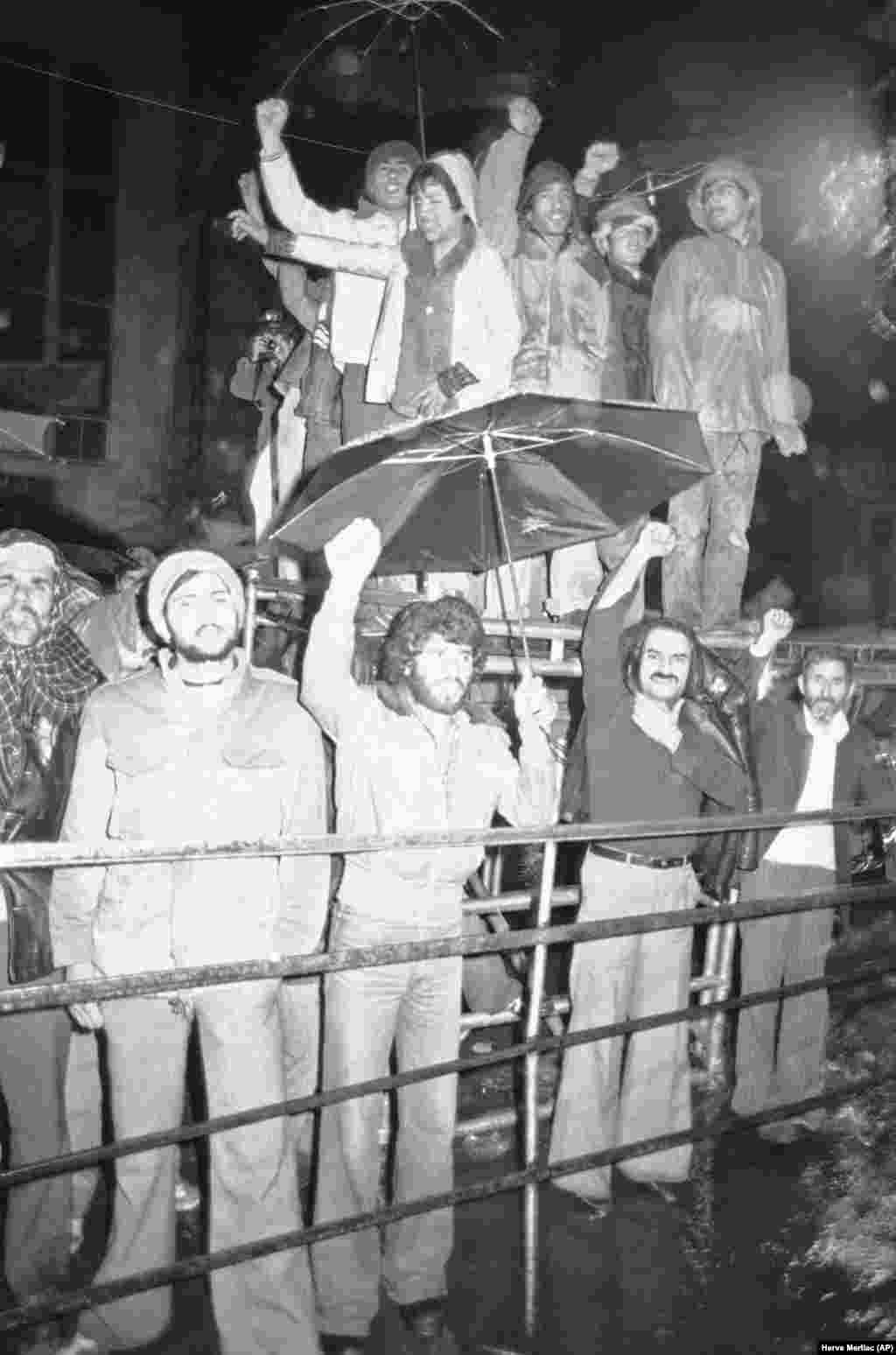 Un grup de iranieni înfruntă un val de ploaie torențială pentru a-și demonstra solidaritatea cu studenții care îi țin ostatici pe cetățenii americani. 15 decembrie 1979, la scurt timp după anunțul că șahul a părăsit New Yorkul și a plecat în Panama.