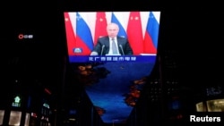 Ruski predsjednik Vladimir Putin na ogromnom ekranu koji emituje vijesti o virtuelnom sastanku između njega i kineskog predsjednika Xi Jinpinga u tržnom centru u Pekingu 15. decembra 2021.