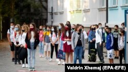 Kosovë: nxënës me maska në gojë si mbrojtje prej COVID-19, duke pritur para shkollë së tyre (14 shtator, 2020). 