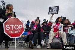 Луѓето држат знаци на денот на „Народниот марш во Вашингтон“ пред претседателската инаугурација на новоизбраниот претседател Доналд Трамп, во Вашингтон, САД, 18 јануари 2025 година.