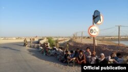 Afghan border guards who fled to Tajikistan after a Taliban attack sit on the side of the road on June 22.