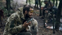 Un soldat ucrainean se joacă cu un câine în timp ce se odihnește pe teritoriul eliberat din regiunea Harkov. (AP Photo/Kostiantyn Liberov)