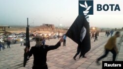 Një luftëtar i IS-it me një flamur të grupit ekstremit dhe me një pushkë në dorë. Fotografi nga arkivi.