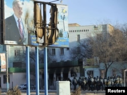 Вооруженные полицейские на улице Жанаозена рядом с поврежденным билбордом с изображением президента Нурсултана Назарбаева. 19 декабря 2011 года.
