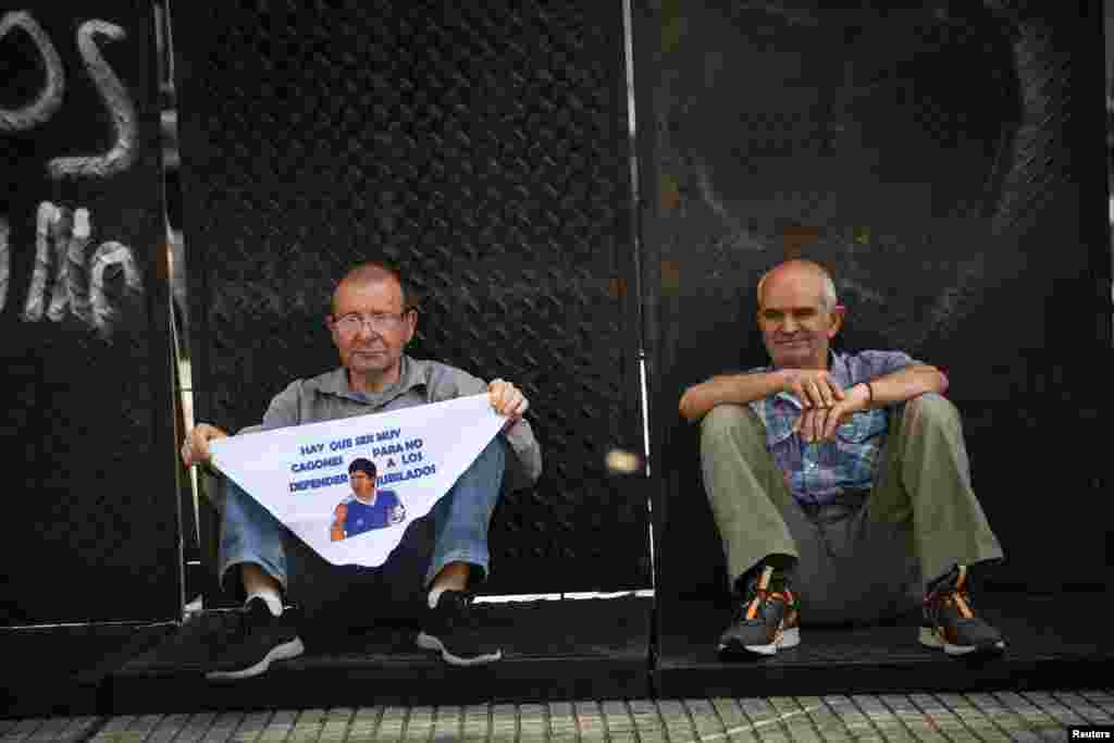 „Nagyon gyávának kell valakinek lennie ahhoz, hogy ne védje meg a nyugdíjasokat” – olvasható az idézet az argentin futball-legenda Diego Armando Maradonától egy kendőn, amelyet egy nyugdíjas férfi tart a kezében a magasabb nyugdíjakért szervezett demonstráción Buenos Airesben 2025. október 15-én