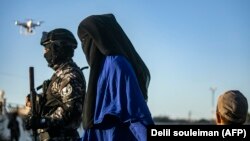 A Central Asian woman linked to Islamic State is escorted by U.S.-backed forces in the northeastern Syrian city of Qamishli in May.