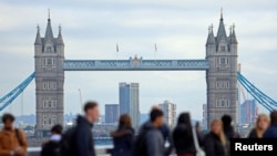 Járókelők London pénzügyi negyedében, háttérben a Tower 2023. október 25-én