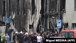 Rendőrök és mentősök az épület előtt, amelybe az üzletember repülőgépe becsapódott Milánóban 2021. október 3-án