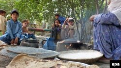 FILE: Children displaced from the North Waziristan tribal region wait as their mother prepares a meal at a temporary shelter in Bannu, June 2014.