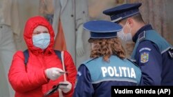 Полицаи проверяват документите на румънка, след като властите наложиха ограничения в придвижването, за да забавят разпространението на епидемията от коронавирус