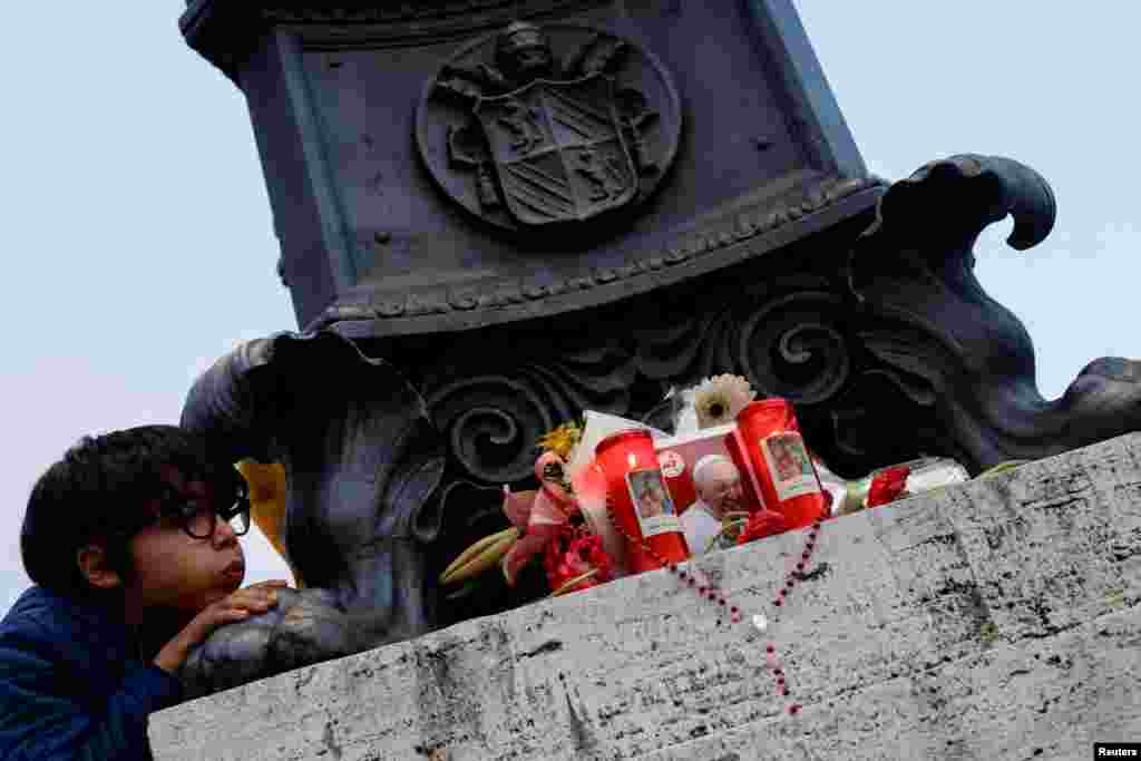 Leo, 9 vjeç, përpiqet t'i fryjë qirinjtë e vendosur pranë një fotografie të Papa Françeskut, ndërsa njerëzit marrin pjesë në luftjet pas vdekjes së papës, në Sheshin e Shën Pjetrit, në Vatikan.