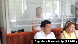Сайрагуль Сауытбай (за стеклом) и ее адвокат Абзал Куспан (внизу слева) на заседании суда в Жаркенте, 13 июля 2018 года. 