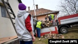 A közmunkásokat foglalkoztató Dehusz Kft. dolgozói tűzifát pakolnak egy rászoruló udvarán Debrecenben 2020. január 20-án