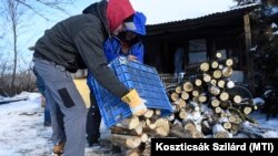 Adománytűzifát pakolnak le egy háznál a Cserkeszőlő-környéki tanyavilágban 2019. január 9-én