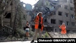 Workers clean up outside a building destroyed as a result of Russian shelling in Mykolayiv on August 2.