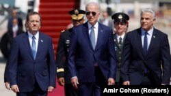Prim-ministrul israelian Yair Lapid (dreapta) și președintele Isaac Herzog (stânga) îl salută pe președintele american Joe Biden, care a aterizat pentru o vizită de trei zile la Aeroportul Internațional Ben Gurion, lângă Tel Aviv, pe 13 iulie.