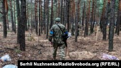 Një ushtar ukrainas duke hetuar një varrezë masive afër Izjumit.