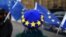 EU flag -themed beret while waving EU flags