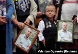 Rodbina drži portrete ukrajinskog vojnika, koji je poginuo u sukobu na istoku Ukrajine, tokom mitinga u avgustu 2020. u znak sjećanja na šestu godišnjicu bitke za Ilovajsk.