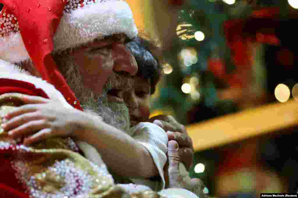 Muškarac obučen kao Deda Mraz grli dijete tokom proslave praznika u Brazilu, 11. decembra 2024.