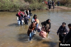 Sirijski Alaviti, koji su pobjegli od nasilja na zapadu Sirije, hodaju kroz vodu rijeke Nahr al-Kabir u Akkaru, Liban, 11. marta.