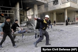 Представители "Белых касок" несут на носилках пострадавшего от авиаудара в Восточной Гуте, 20 февраля 2018 года