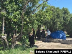 დაზარალებულები დამწვარ ბაზრობასთან იცდიან და ჩრდილს არაფერებენ თავს.