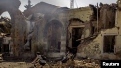 Едно лице поминува со велосипед покрај железничката станица која беше оштетена од повеќекратно гранатирање во Костјантинивка во источна Украина.